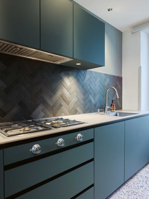 Die geradlinige Küche mit der minimalistischen Axor-Armatur und dem cleanen Spülbecken von Suter Inox steht im spannenden Kontrast zur Ehrwürdigkeit des Hauses.