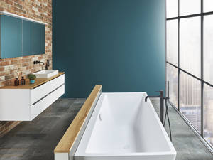 Die Wandkeramik in Backsteinoptik trifft auf warme Holzdetails und ein geradliniges Design von Badewanne und Waschbecken. Sabag.