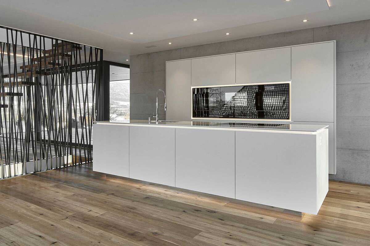 Die grifflosen Fronten unterstreichen den minimalistischen Stil der Küche. Bei der schwebend wirkenden Arbeitsplatte handelt es sich um den Kunststein «Silestone Blanco Zeus». Furrer Küchen AG.